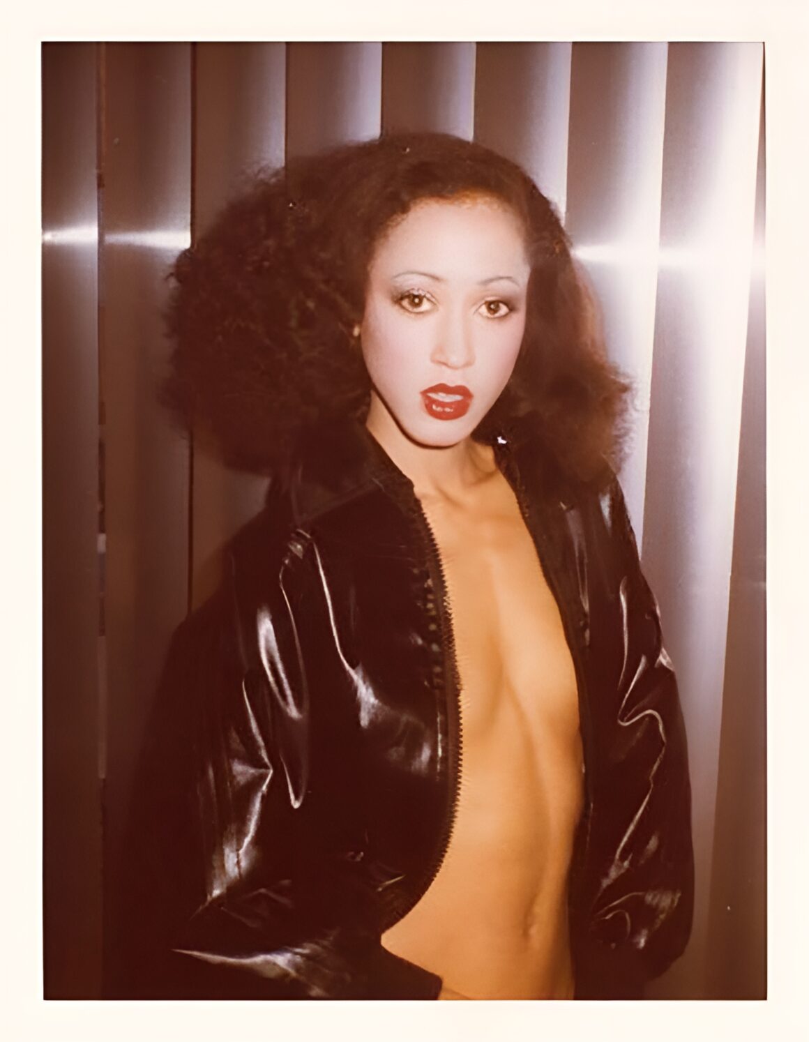 Photo of model Pat Cleveland wearing a black jacket and bright red lipstick