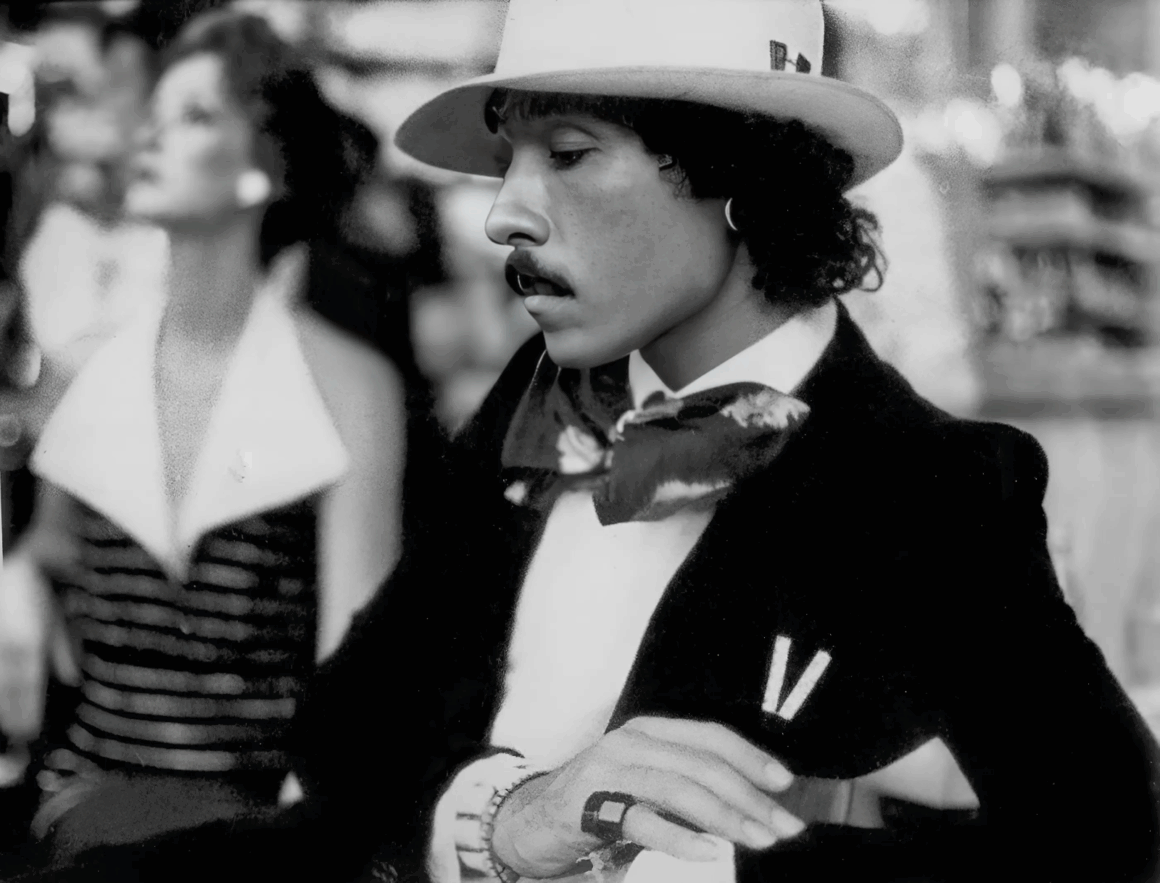 Photo of Antonio Lopez wearing dark blazer with scarf and hat