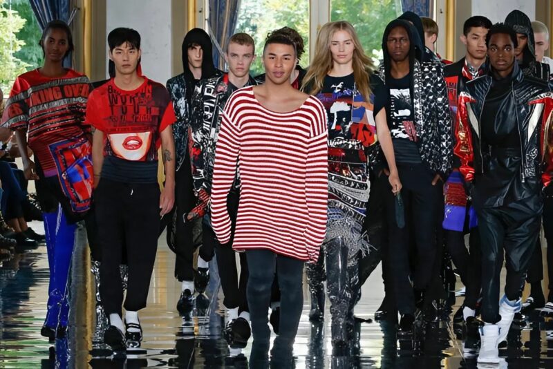 Oliver Rousteing wearing a red and white strip sweater surrounded by male and female models from Balmain Spring 2019 show