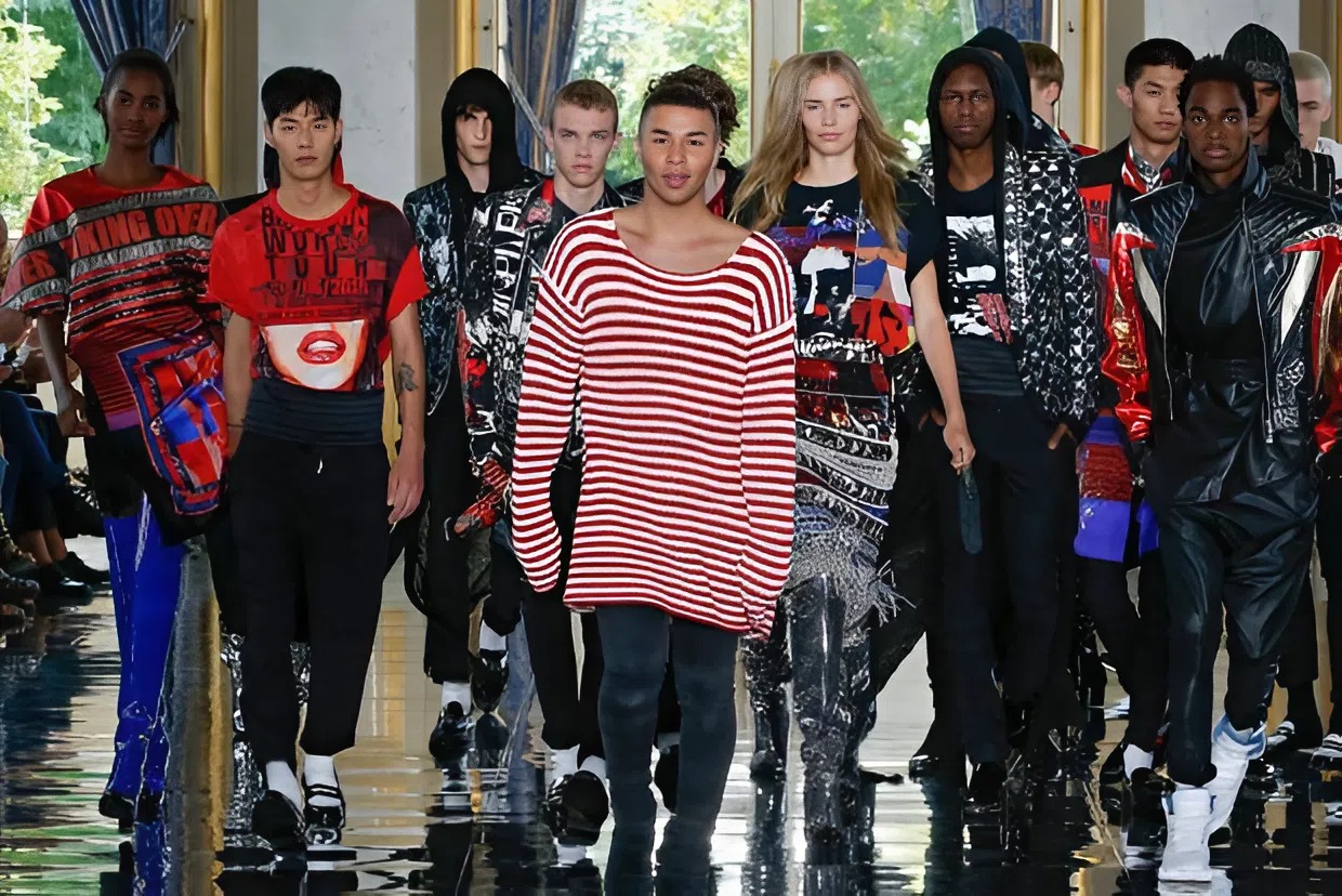 Oliver Rousteing wearing a red and white strip sweater surrounded by male and female models from Balmain Spring 2019 show