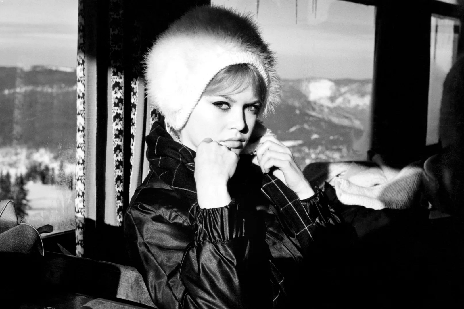 Brigitte Bardo in the 1960s wearing a white fur hat and black coat with scarf