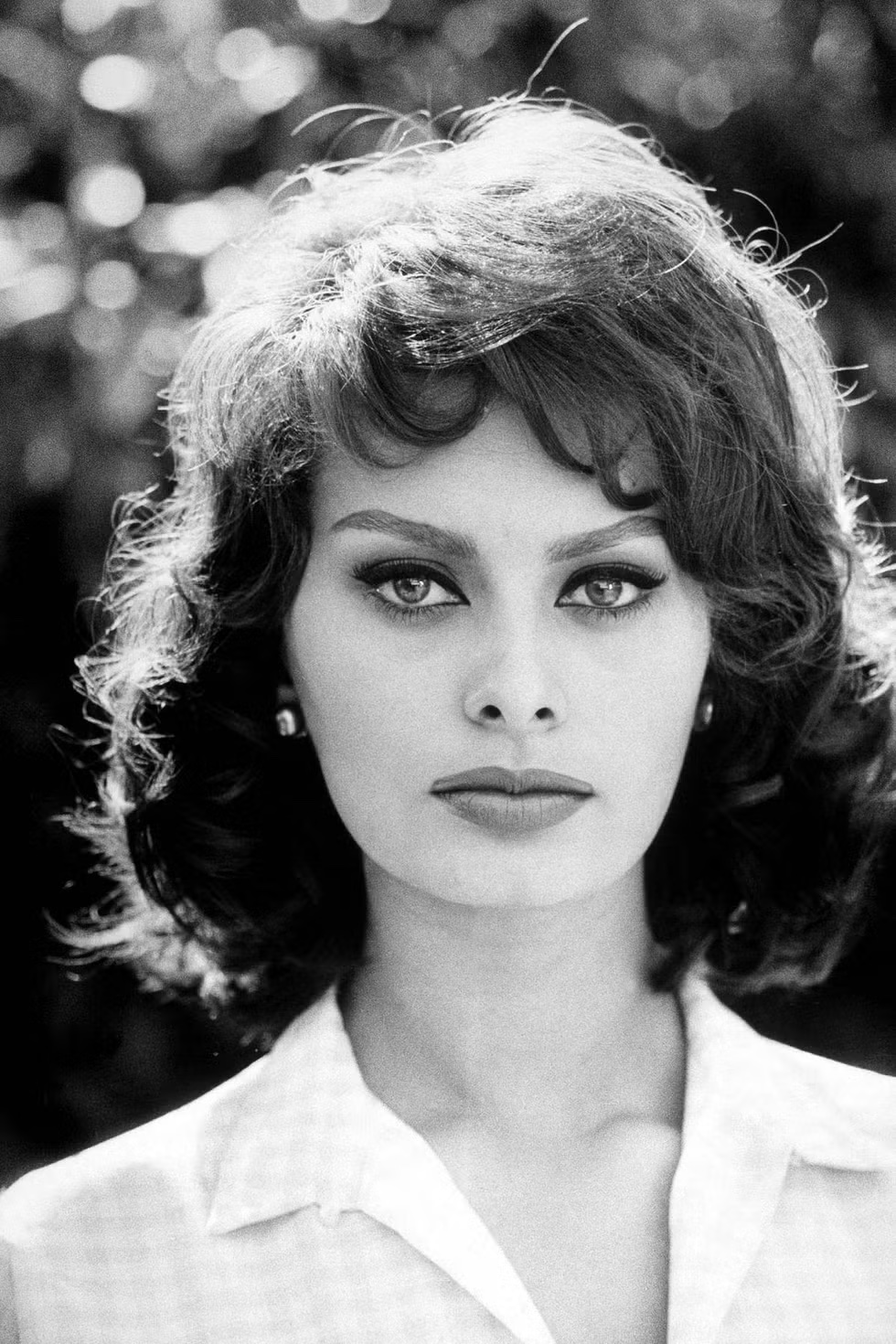Sophia Loren looking into the camera wearing a gingham shirt.